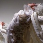Two dancers dancing and wearing white ruffled shirts and wigs 