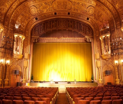 UPCA interior, showing the golden hues, gilded decor, and well-lit stage and seating area.
