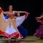 Three Reaction Dance company members dance on a stage with a black backdrop and wood floor.
