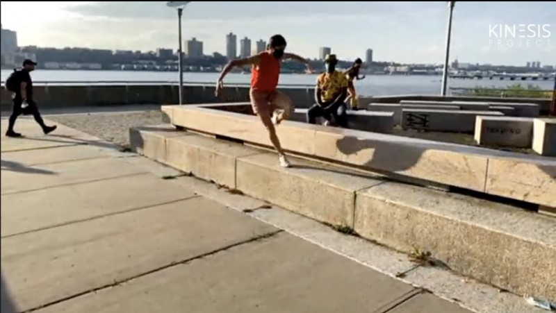 A dancer in a red top and shorts balances on a concrete step in Riverside Park, behind her is the narrator