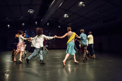 Several people holding hands and dancing in a circle.
