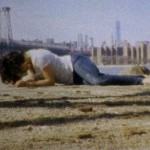 Image of a woman faced down crawling in front of a city skyline 