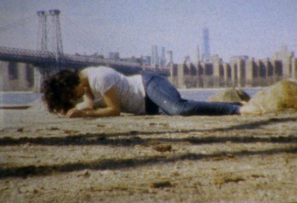Image of a woman faced down crawling in front of a city skyline 