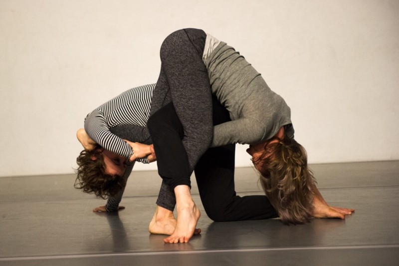 Two dancers holding onto each other's arms through their legs