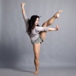 female dancer balancing on one leg with other leg extended in the air. Arms are also extended and torso is contracted.
