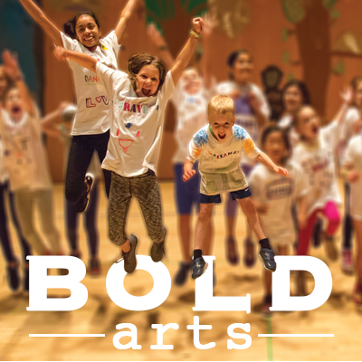 Three smiling children with their arms stretched upwards jumping over text that reads "BOLD Arts"
