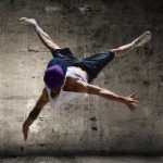 a break dancer in mid air creating an X shape with their arms and legs