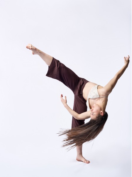 Dancer in maroon pants with leg in the air.
