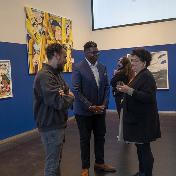 Three people talking at a gallery exhibition opening