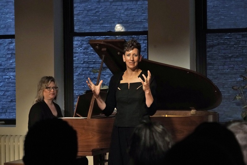 A woman stands in front of a piano while singing during a workshop at the BAC