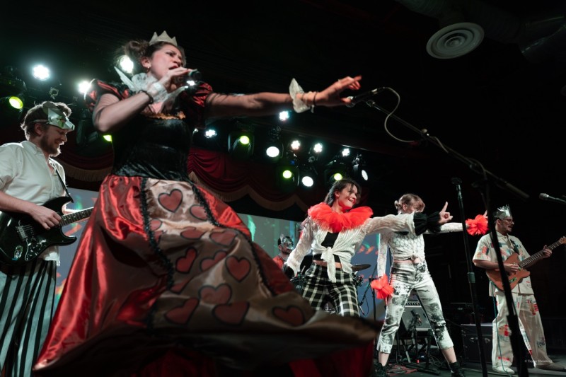 Red queen singing with 2 dancers