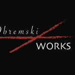 Obremski/Works Logo with a red cross in between "Obremski" and "Works" in front of a black backdrop