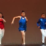 3 young Dominican Latin dance students on stage wearing red and blue - two girls and one boy