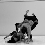 Three dancers support each other in a sculptural shape.