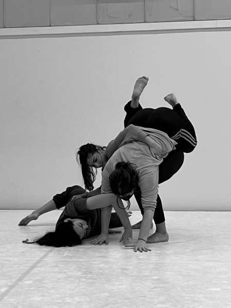 Three dancers support each other in a sculptural shape.