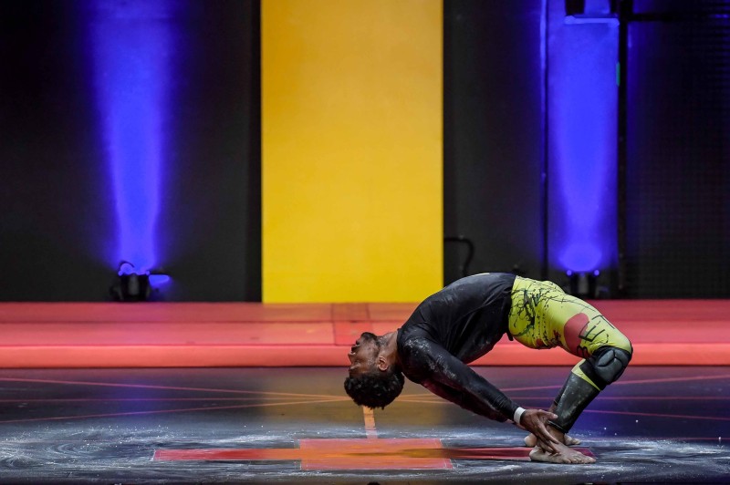 A dancer dressed in yellow leggings and a black shirt hinges backward