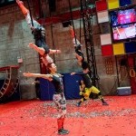 A duet of double stacked dancers stand proudly with arms extended. 