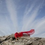 A dancer on rocks with a long red veil trailing behind her