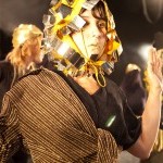 A dancer wearing a metallic costume performs onstage 