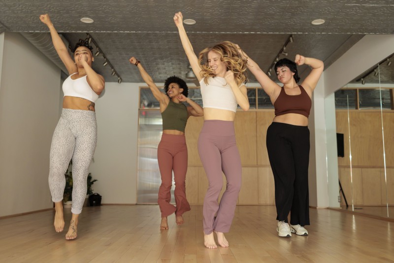 four dancers are jumping with one arm raised in the air