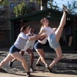 Three dancers dancing outside with one dancer lifting one leg