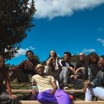 A group of people smiling and laughing outdoors as they sit on bleechers.