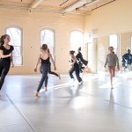 A group of dancers in motion in a studio.