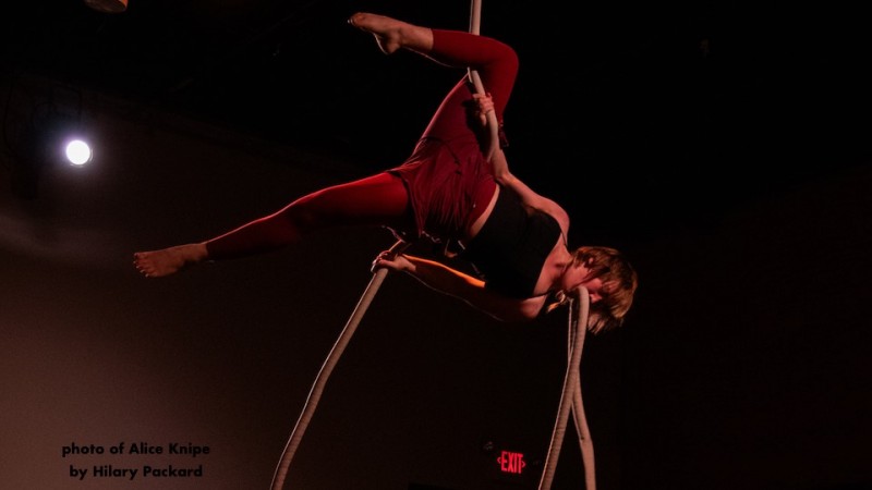 invented aerialist has rope wrapped around their back and the tail end held in their teeth