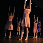 Photo of the work of Paige Nelson at Small Plates Metuchen 2019. Four women in pink dresses stand with arms reaching up.