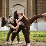 Three dancers leaning in a park