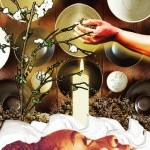 collage: a Black person in profile, empty bowls, flowering tree, lit white candle, black hands cradling dirt and white cloth