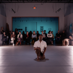 Image of a male dancing kneeling on a white floor