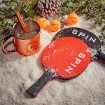 Image of two ping pong paddles on top of a snowy decor with a drink and leaves behind them 