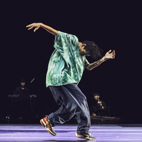 Korean dancer in a mint green shirt and jeans, mid-motion