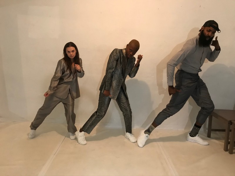 3 dancers in suits in a movement sequence in the studio