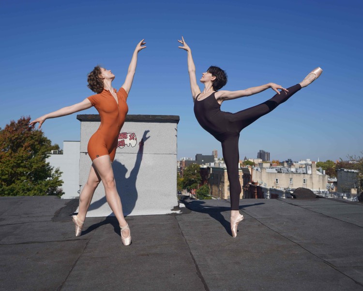 Two dancers on pointe on a roof. One is in fourth position and the other in arabesque