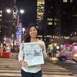 A lady holds a copy of the newspaper in Times Square