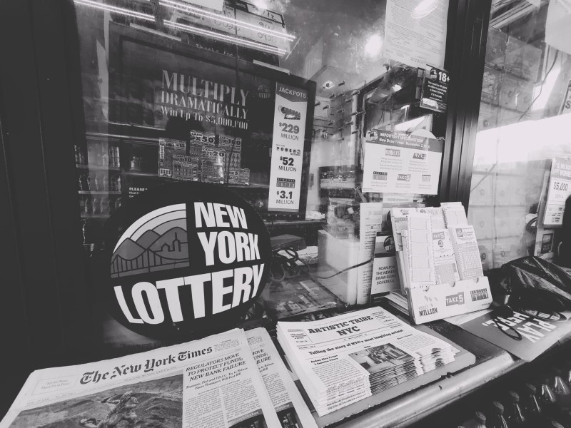 A pile of Artistic Tribe NYC's newspaper is shown next to The New York Times in a deli. 