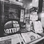 A pile of Artistic Tribe NYC's newspaper is shown next to The New York Times in a deli. 