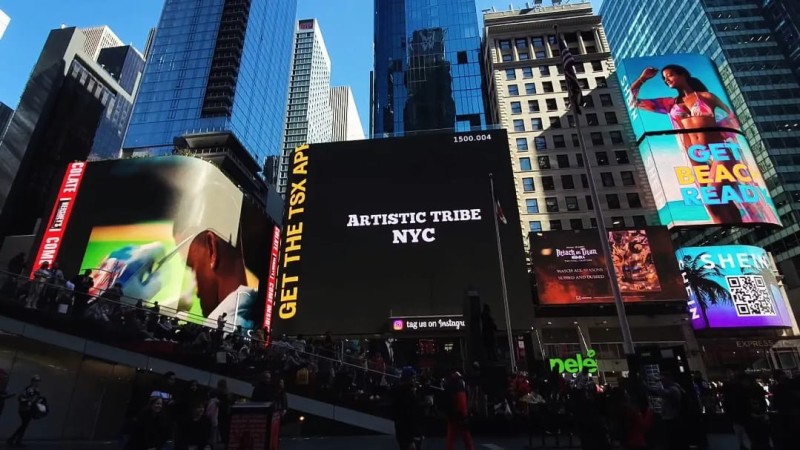 A billboard shows the logo of Artistic Tribe NYC