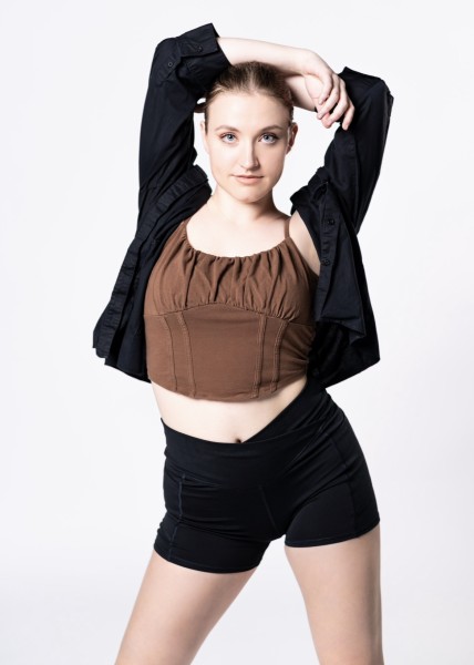 Photo of Dancer posing with arms draped over her head. 