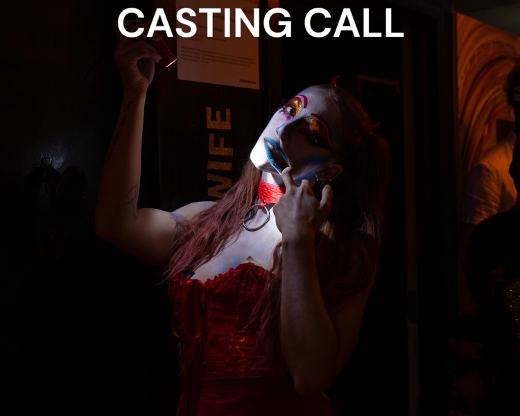 Locke in theatrical zombie drag -esque make up holding a flashlight to their face with the title 'casting call'