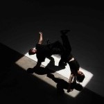 two dancers upside down in a bridge position with their shadows cast below them