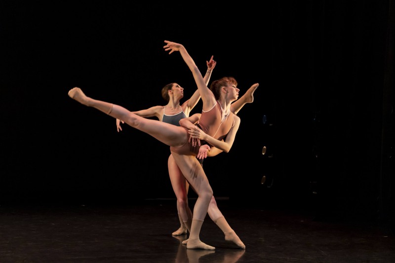 Three female ballerinas form a structured, overlapping pose