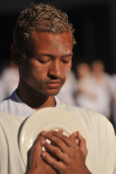 Male dancer with eyes closed clutching a white ceramic plate to his chest