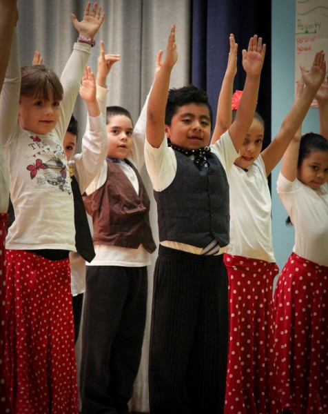 Elementary school students with arms raised above their heads in a flamenco dance class