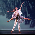 Two ballet dancers on stage; the male dancer lifts the female dancer, who extends her arm gracefully upward.