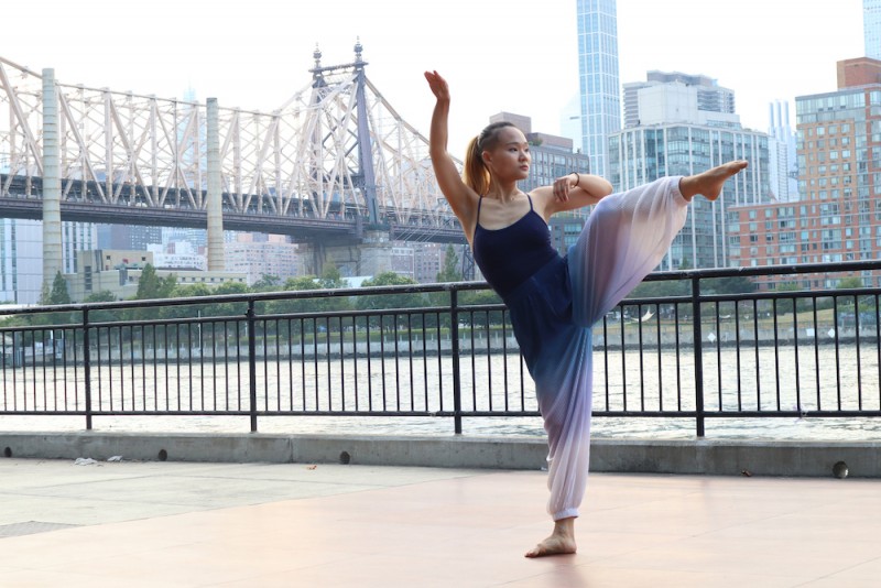 Dancer with arm and leg up in front of Queensboro bridge