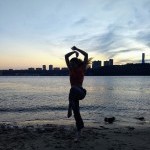 dancer by water, in big skip, arms over head