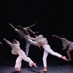 Image with 4 dancers facing back and leaning on one leg and arms extended in front of them